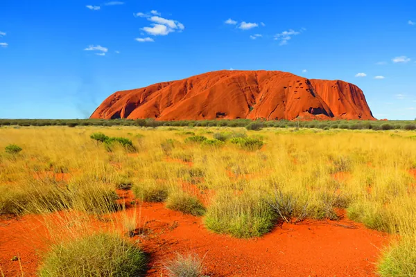 Uluru rising above red earth and spinifex in the Northern Territory