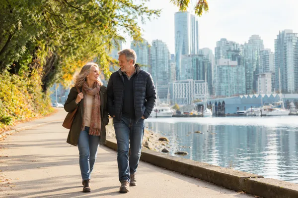 Couple walking along the seawall path with the Vancouver skyline behind