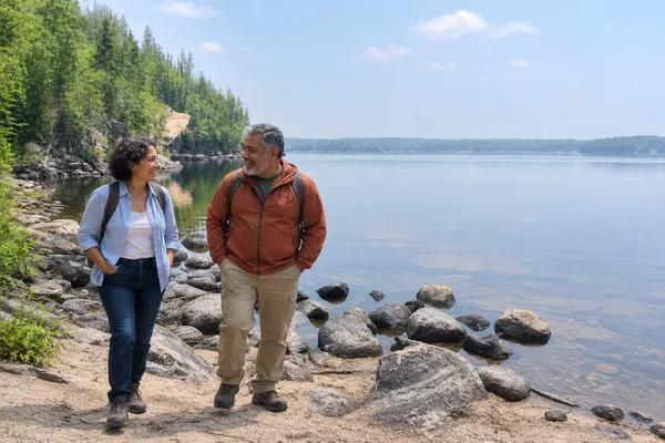 Couple walking along a rocky lakeshore in Nopiming Provincial Park, Manitoba