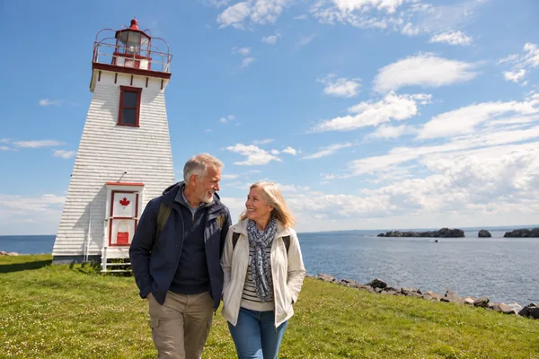 Couple walking past a lighthouse on the New Brunswick coast