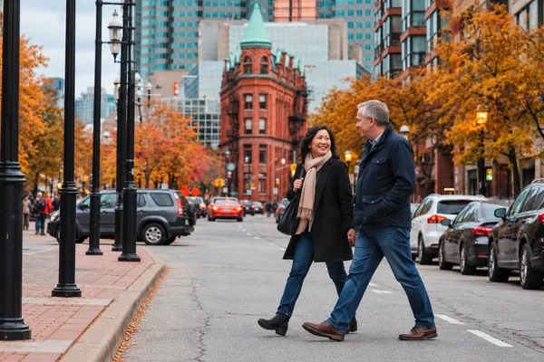 Couple walking past the Gooderham Building in Toronto on an autumn day