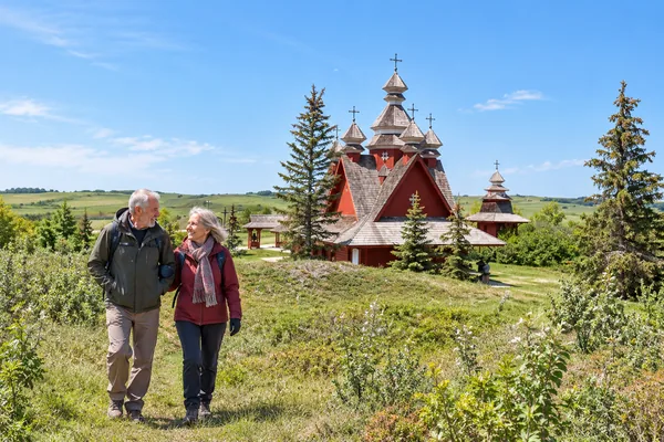 Couple walking past a wooden prairie church in Saskatchewan