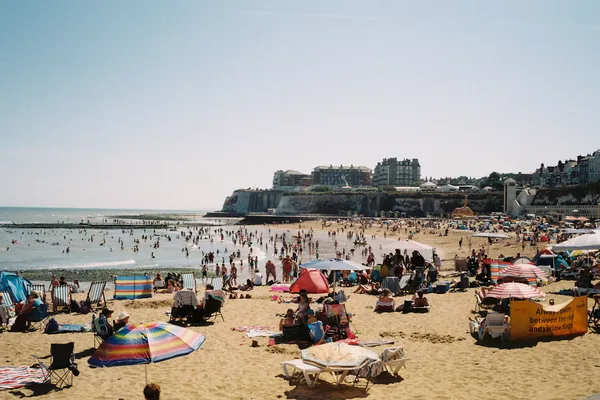 Sunny English beach with deckchairs and parasols beneath chalk cliffs